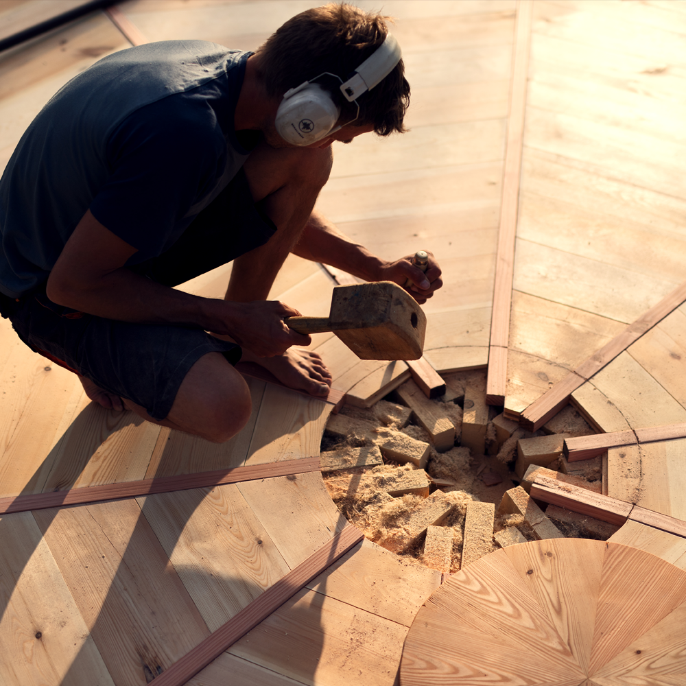 Handwerker fertigt Holzverbindung für Jurtenboden in traditioneller Technik