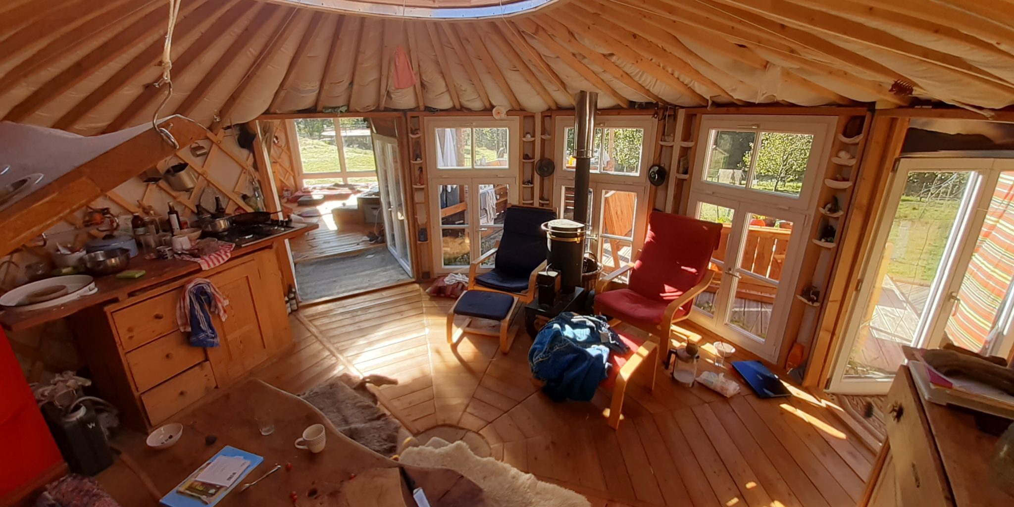 Innenraum einer Jurte mit Sesseln, Tisch und Holzfußboden