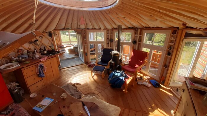 Innenraum einer Jurte mit Sesseln, Tisch und Holzfußboden