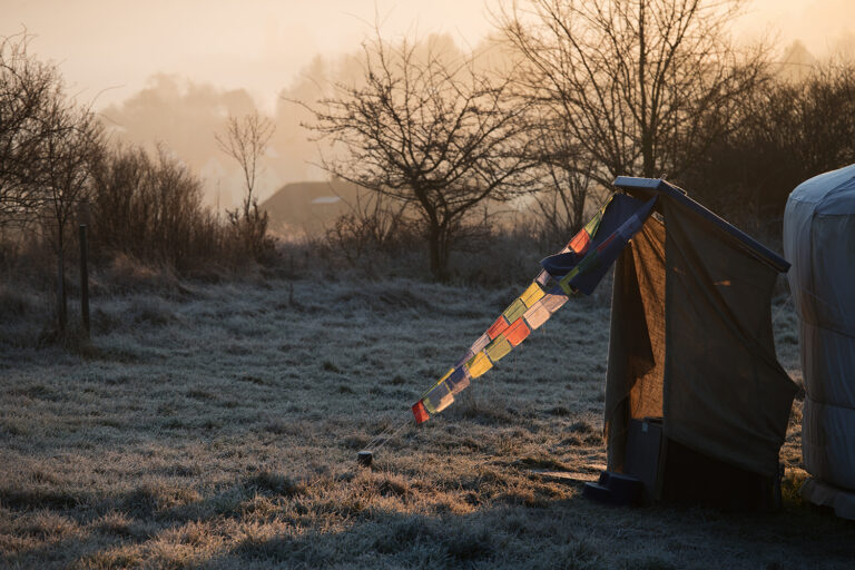 Morgenstimmung mit Gebetsfahnen Gebetsfahnen auf einer frostigen Wiese im Sonnenaufgang