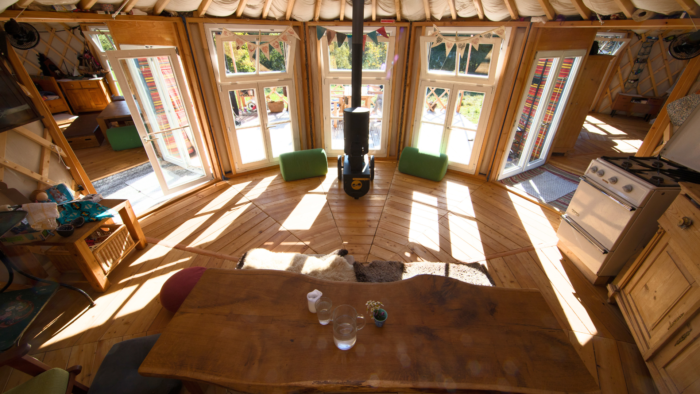 Jurte Inneneinrichtung Blick ins Innere einer Jurte mit Holzboden, Dachkranz und Sonnenlicht durch die Fenster