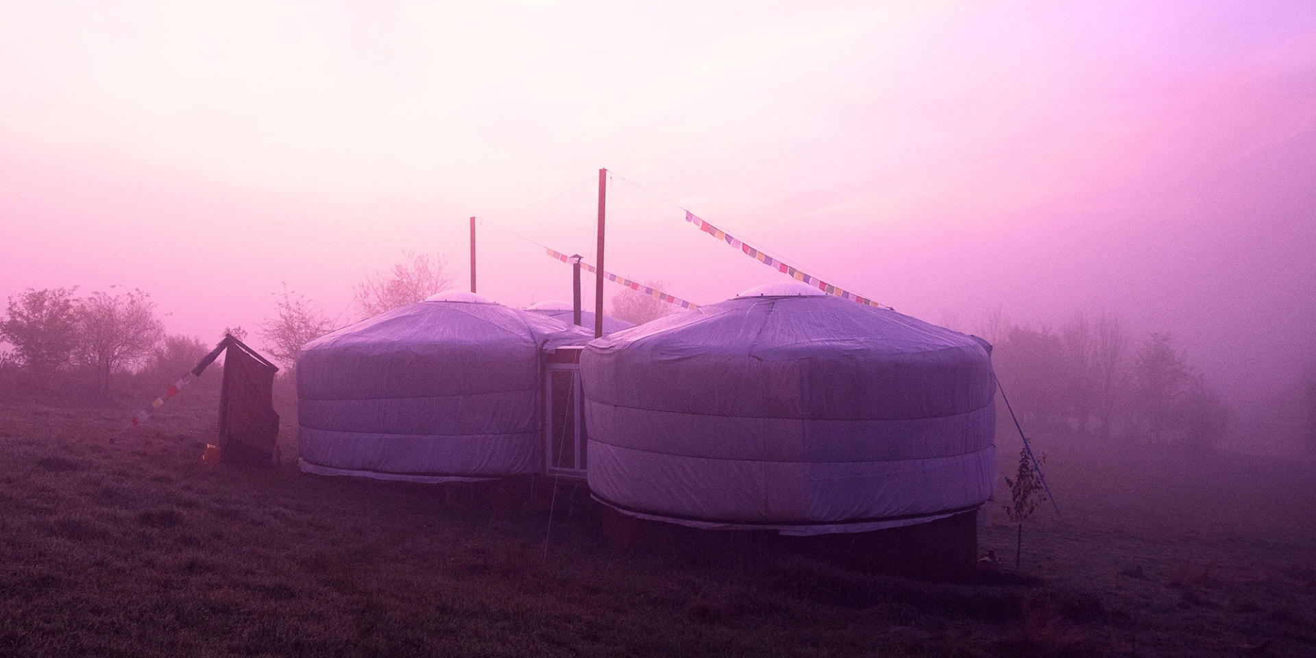 Jurten im Morgennebel Miteinander verbundene Jurten mit Regentuch und Ofenrohr auf einer Wiese im dichten Morgennebel